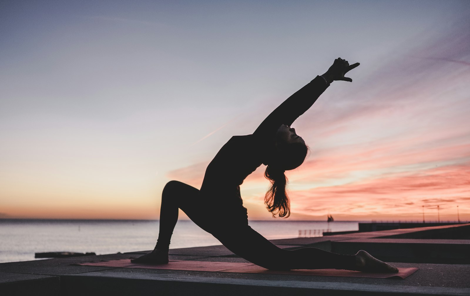 Woman moving through a yoga pose at sunrise